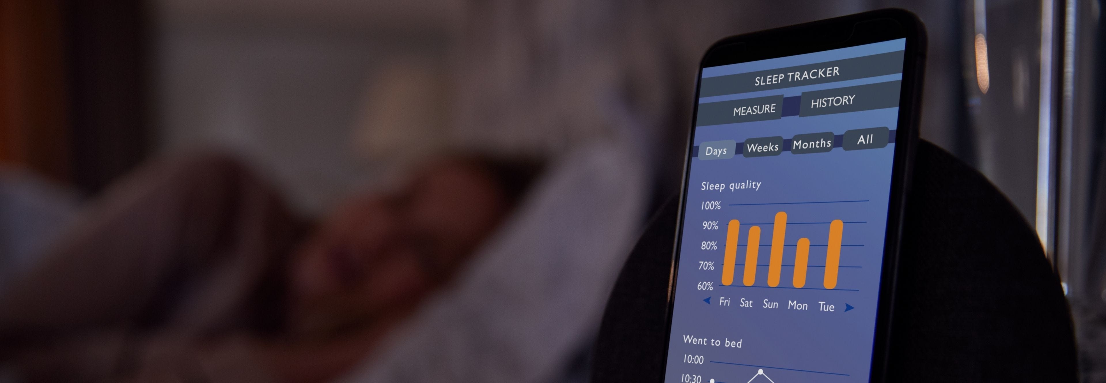 person sleeping next to phone with sleep tracking information on screen