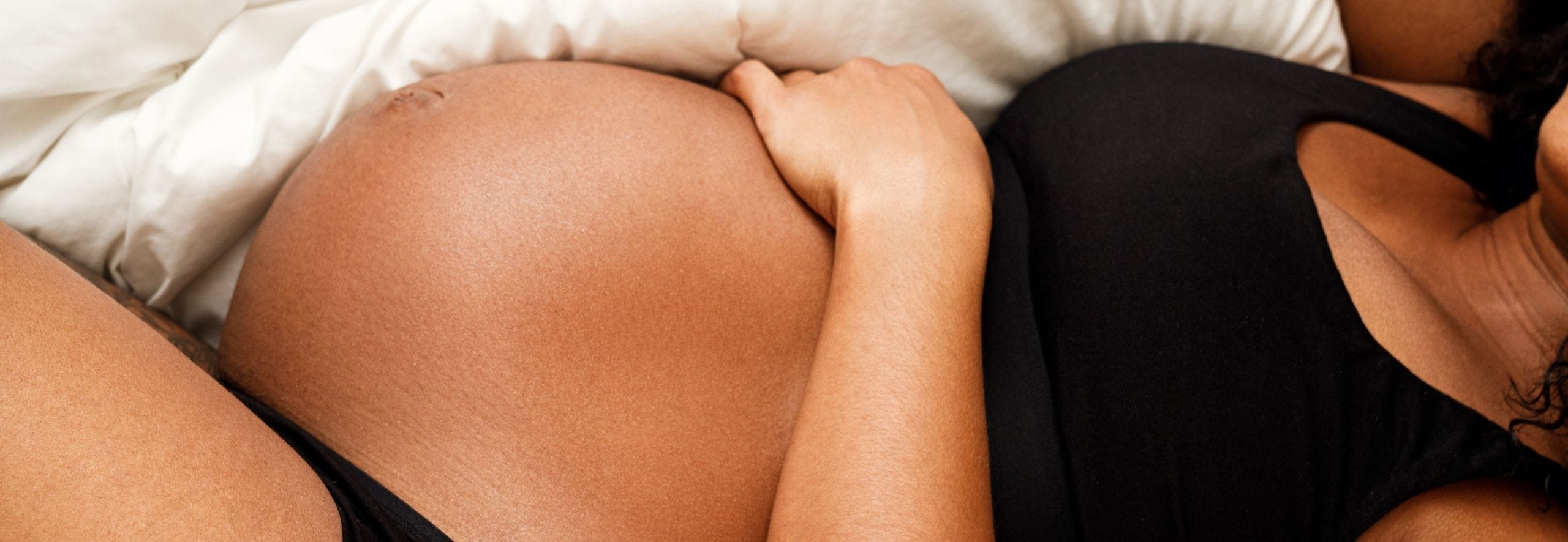 Pregnant woman propped up on pillows, trying to sleep