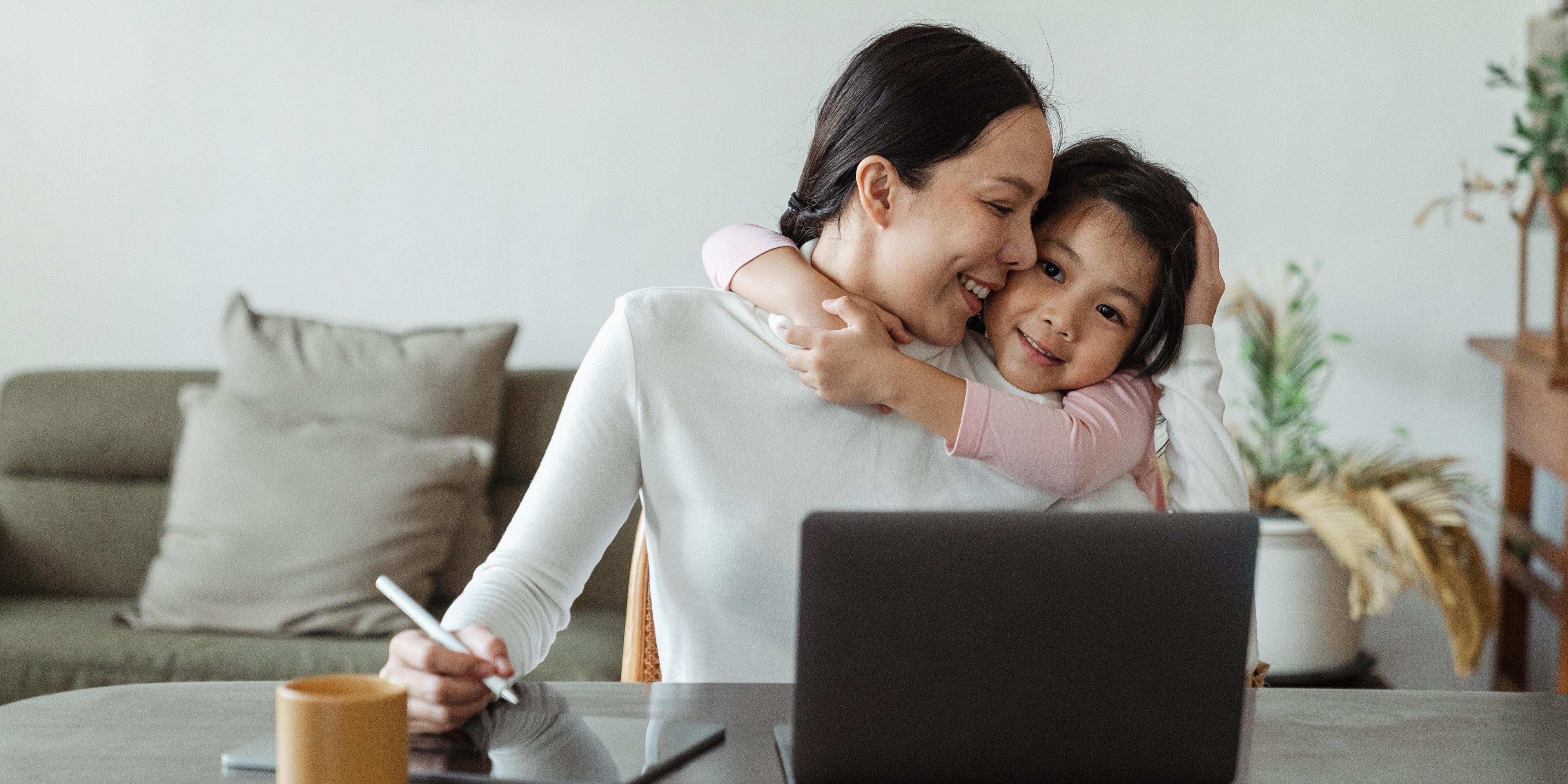 Mom working from home with daughter hugging her