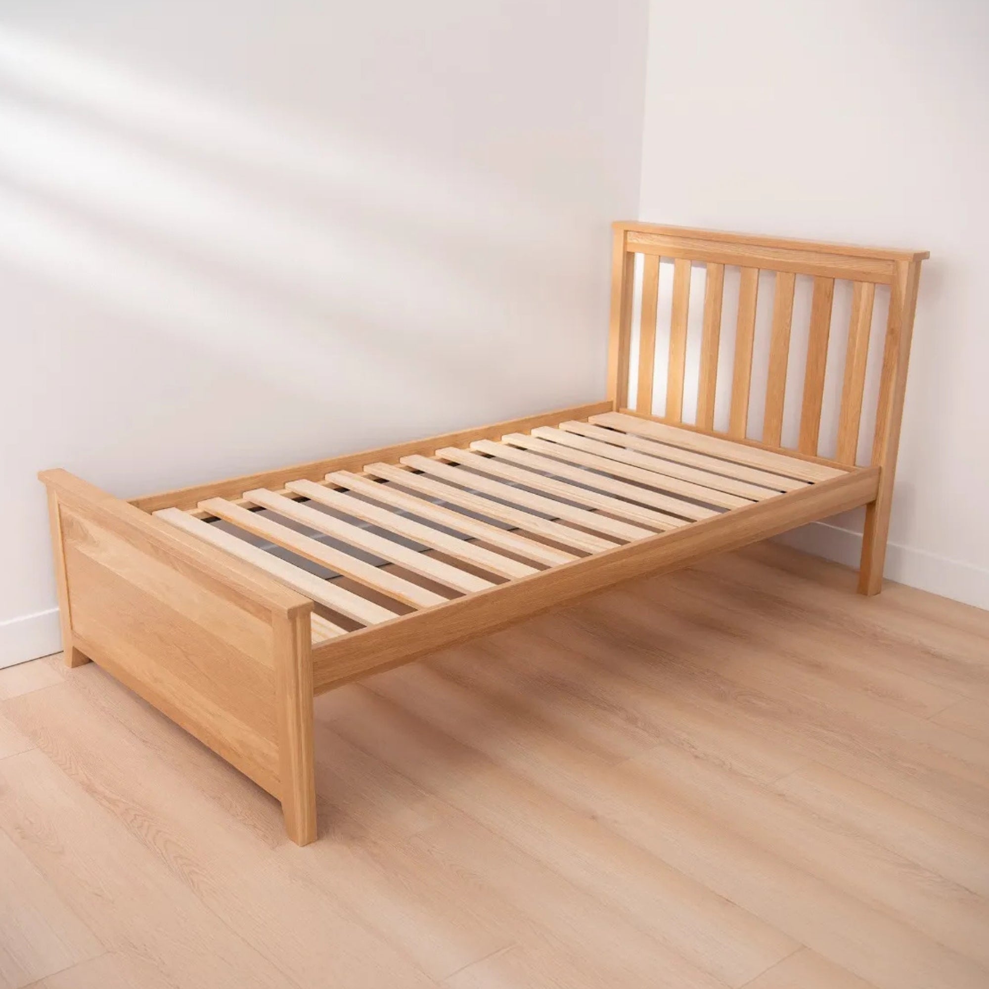 Wooden bed frame on a wooden floor with a white wall background #size_twin platform #color_natural