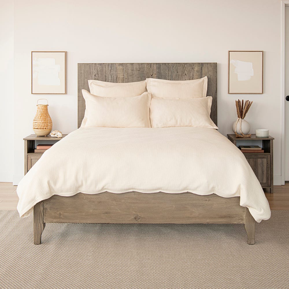 Bedroom with a wooden bed frame, white bedding, and side tables with decorative items.