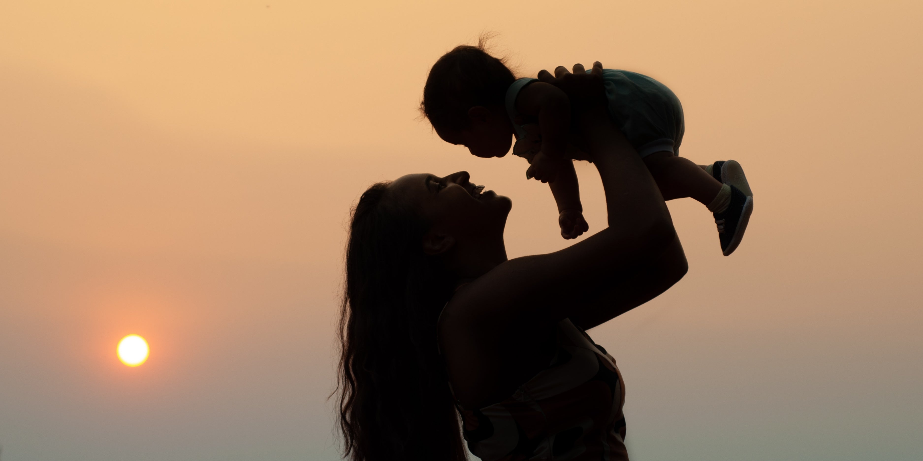 woman holding baby at sundown
