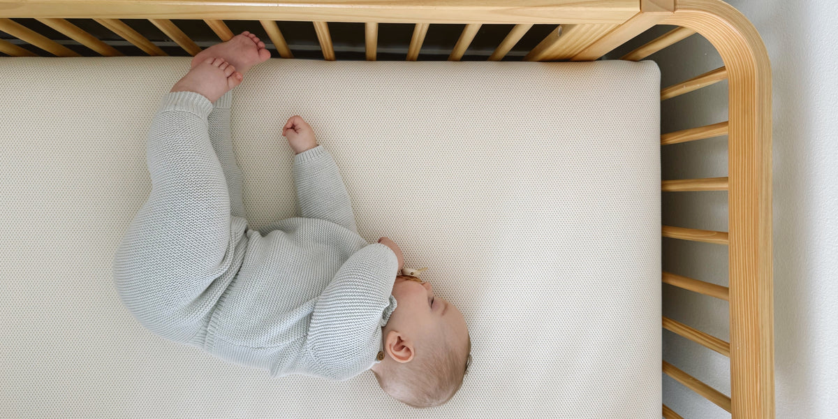 baby sleeping on their side in crib