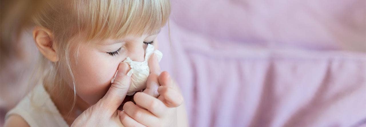 Parent's hand reaching to help child blow her nose