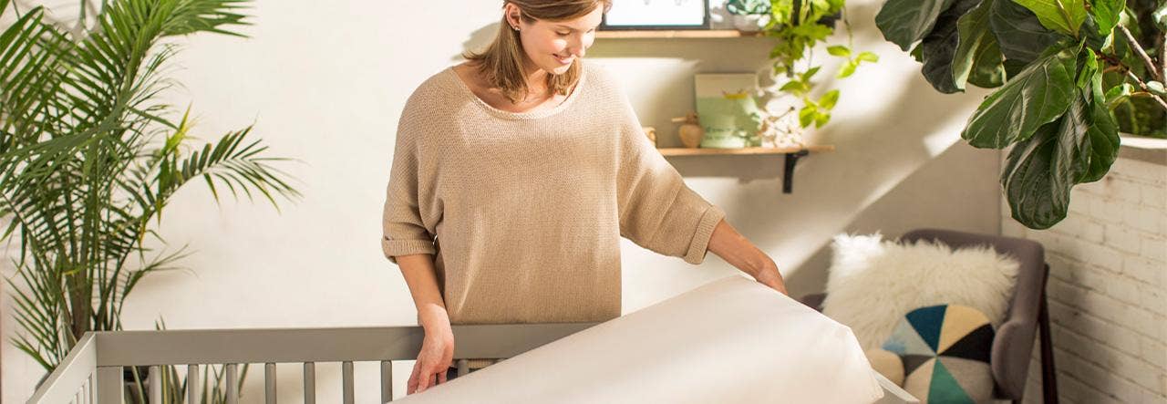 Woman lifting crib mattress and smiling