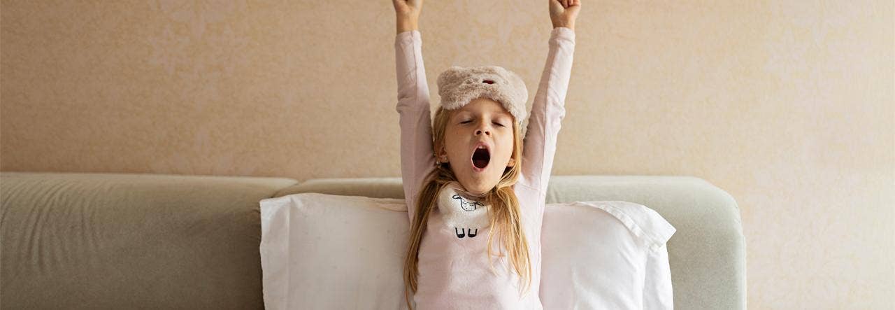 School-aged child yawning and stretching in bed