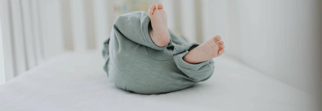 Tiny feet as Baby lies on a crib mattress