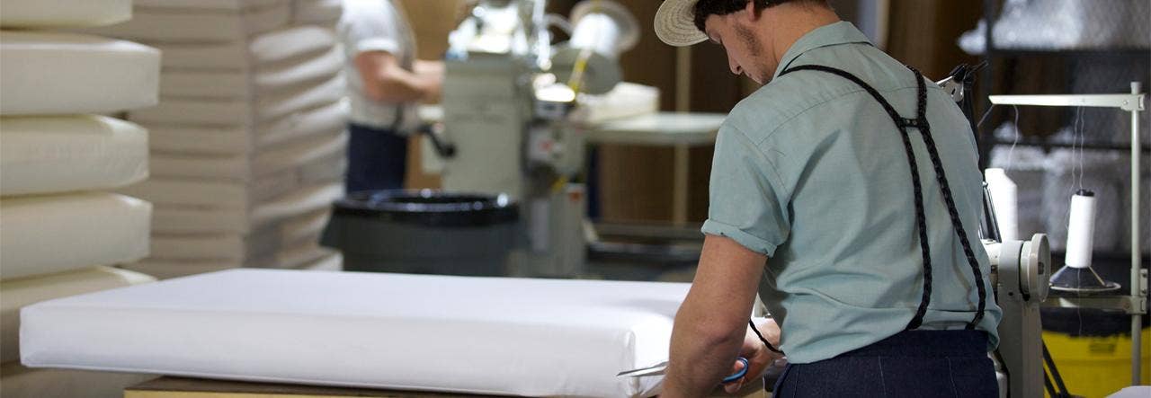 Amish craftsman using scissors to cut organic cotton in factory