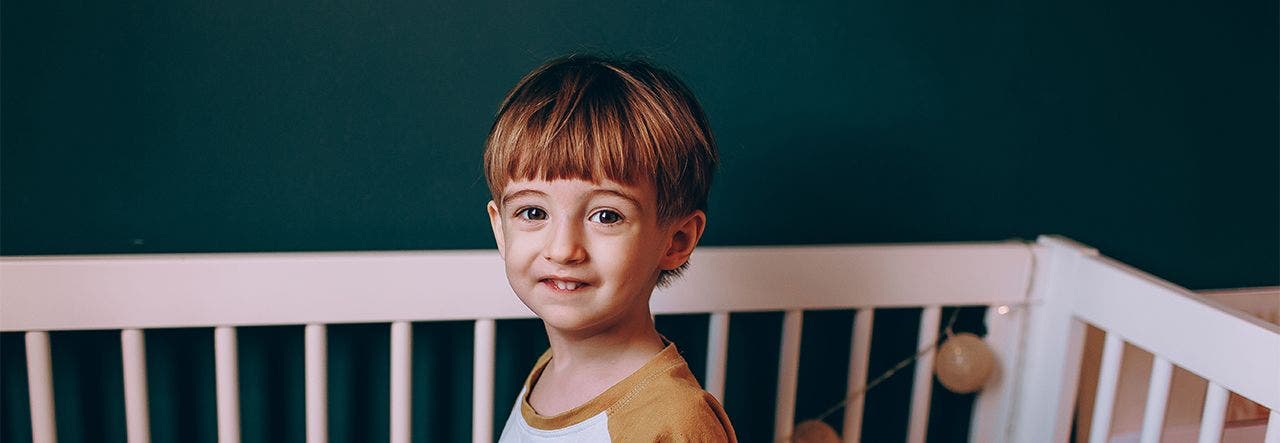 Toddler boy sitting up on his 2-stage mattress