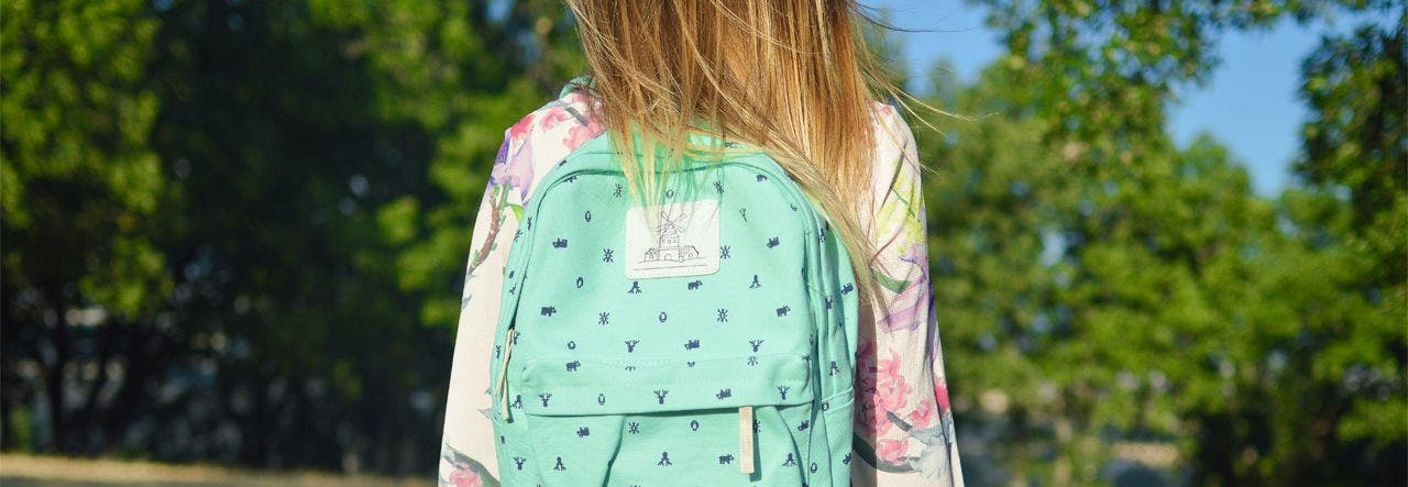 Elementary school girl wearing back pack and facing the road