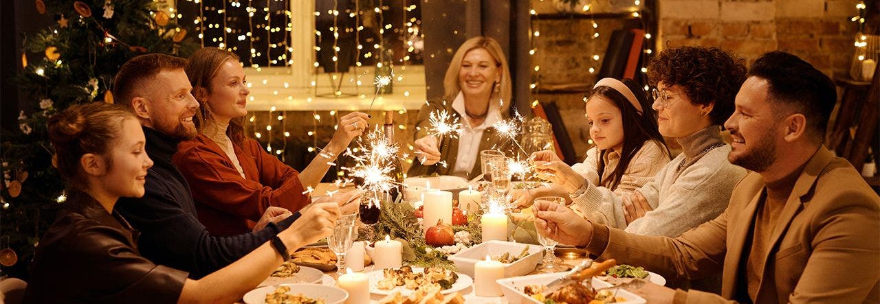 Family celebrating New Year's Eve together with small sparklers around the table