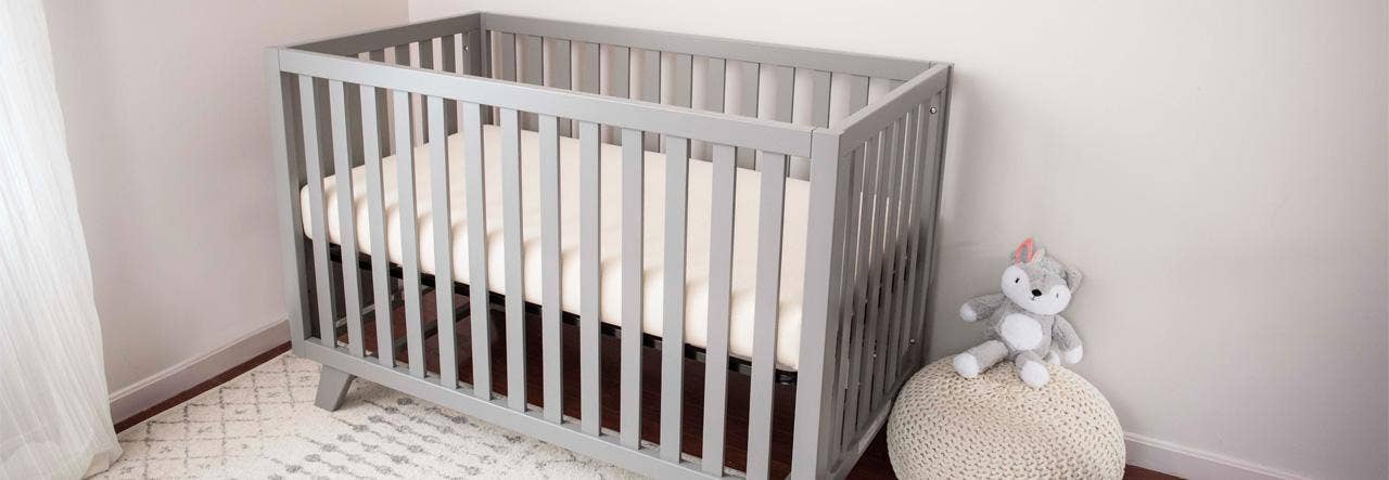 Gray crib in the corner of a nursery 