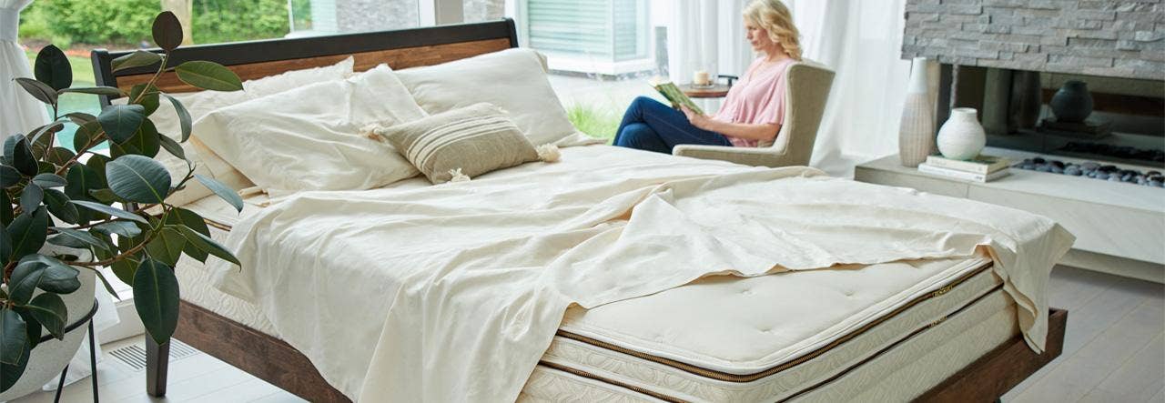 Woman reading on a chair in a clean, naturally lit bedroom