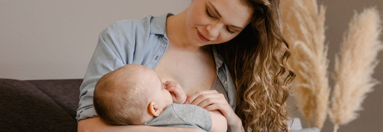 Mother breastfeeding her baby at home