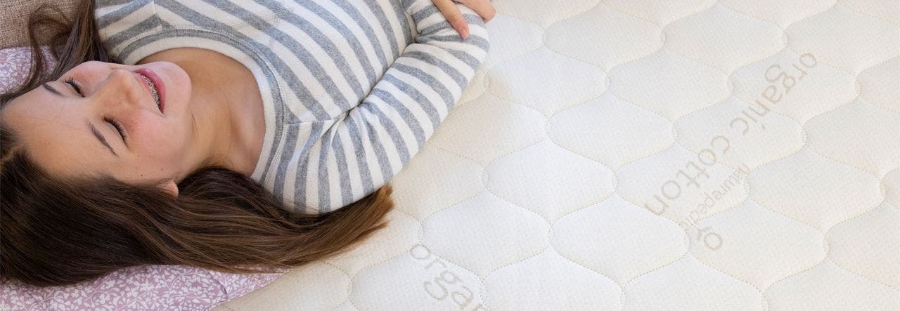 Teenage girl lying on a Naturepedic organic mattress