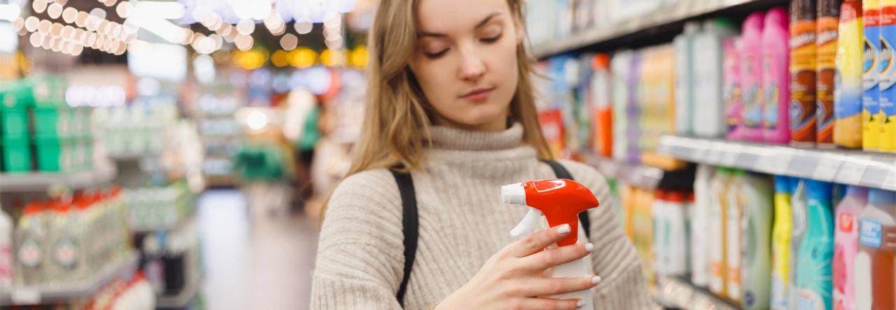 Young woman in the grocery aisle examining cleaning products