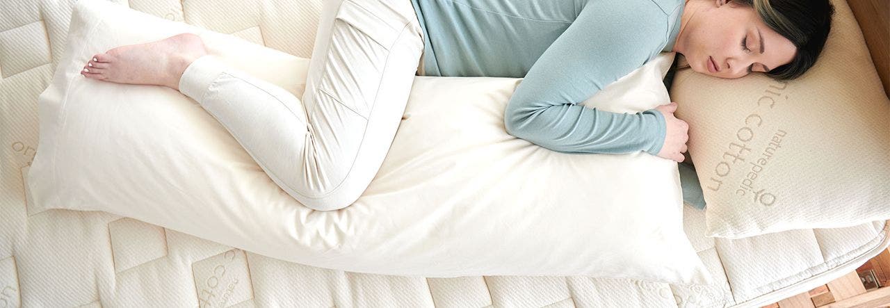 Woman side sleeping with a Naturepedic body pillow