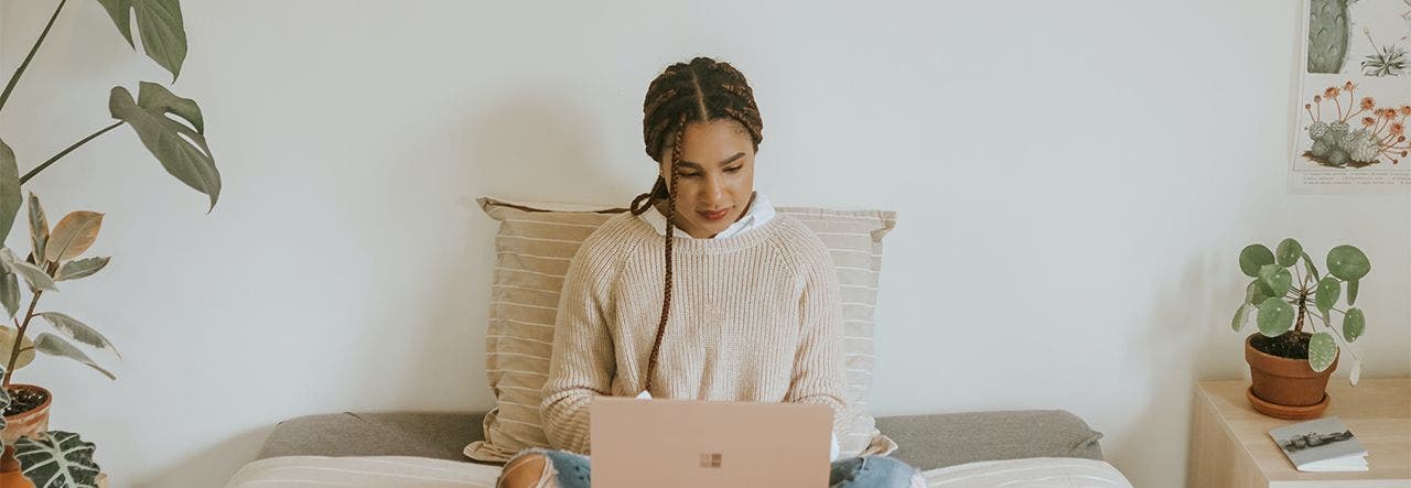 Woman sitting cross-legged on bed and researching environmental toxins