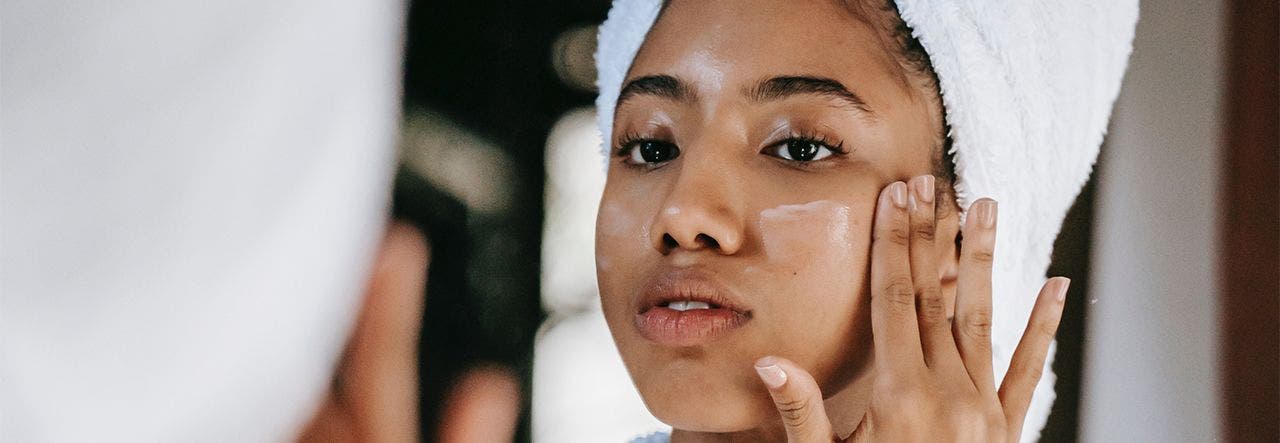 Woman in a bath robe, applying cosmetics that may contain endocrine disruptors