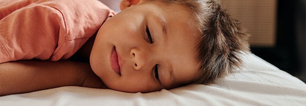 Young boy sleeping face down on his mattress