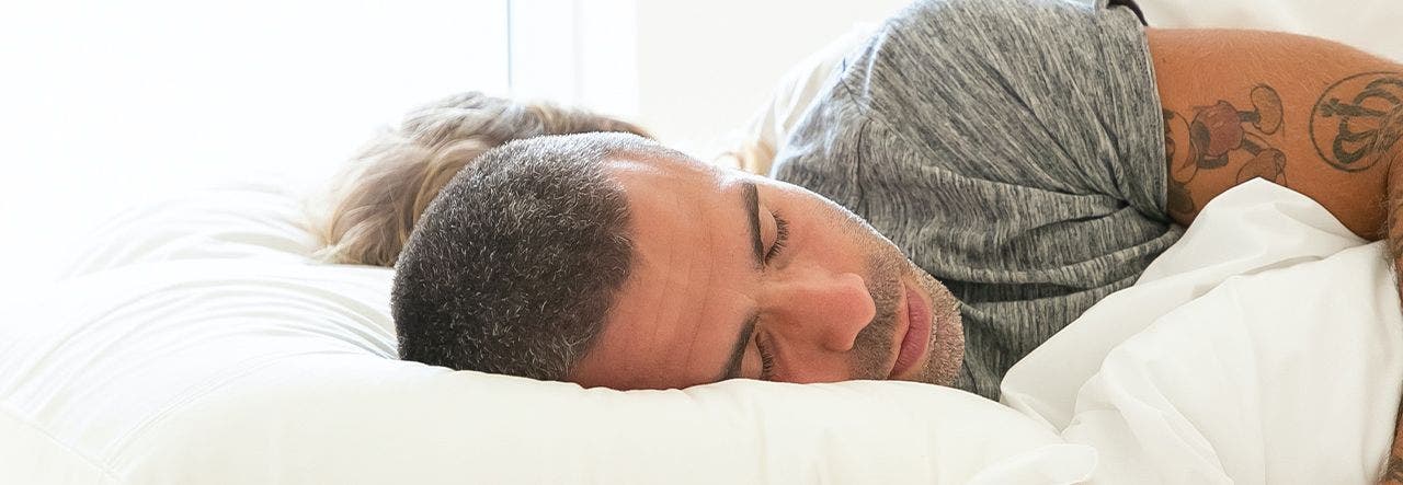 Couple sleeping in bed together, both lying on their sides