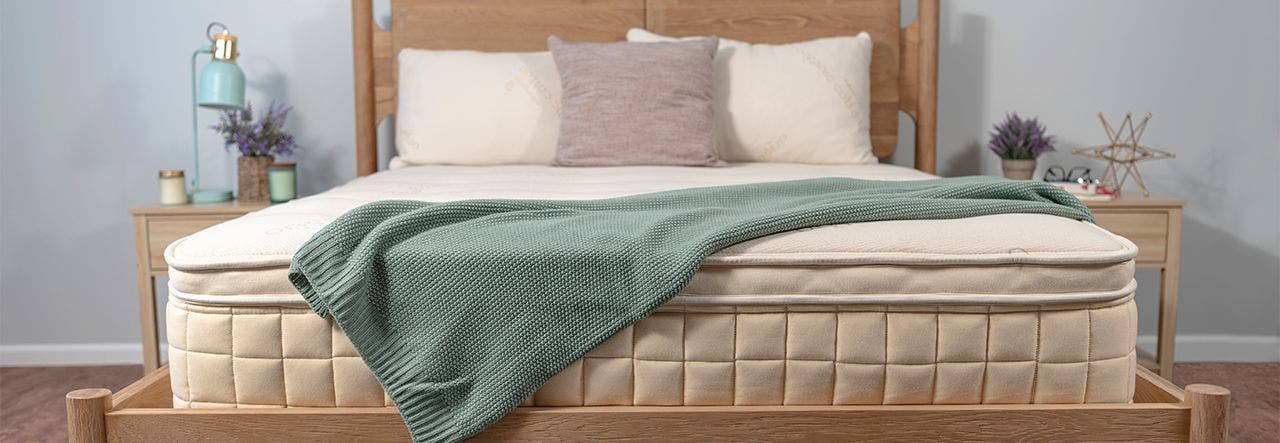 Naturepedic's new Concerto Organic Pillow Top Mattress set up with a green blanket