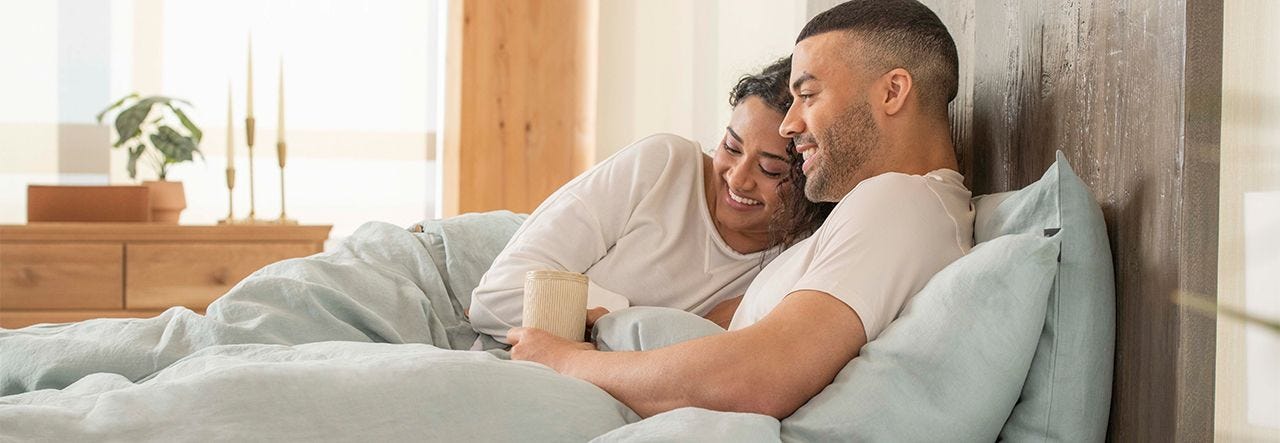 couple cuddling in bed with blue bed sheets