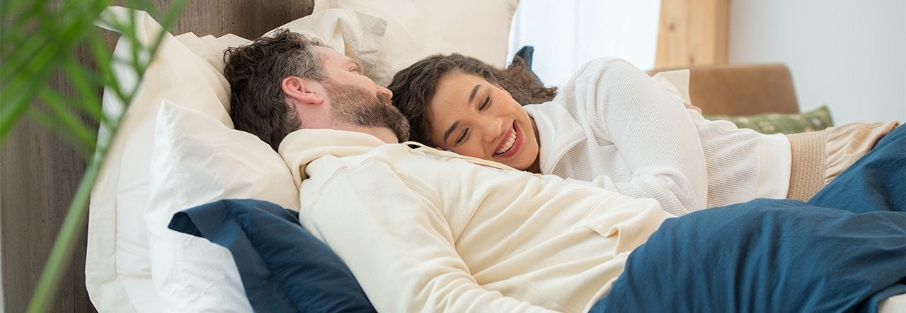 couple cuddling in bed on percale sheets