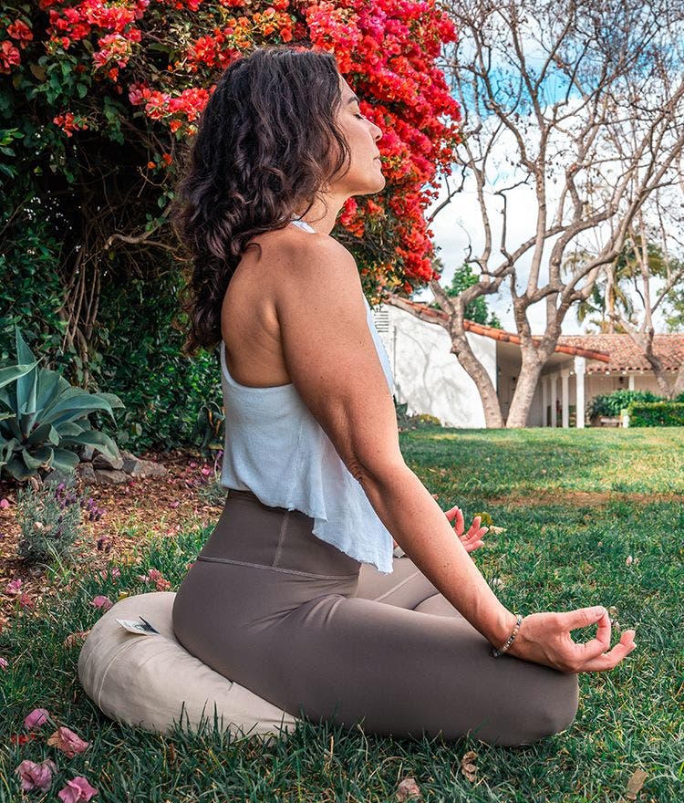 woman meditating outside on a naturepedic meditation cushion