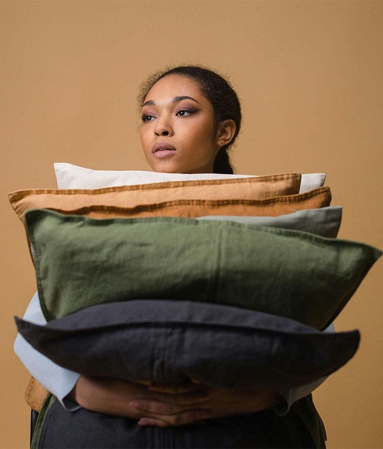 woman holding a stack of multicolored pillows