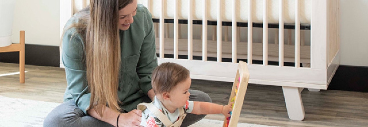 Mother and baby playing with wooden toy on the floor