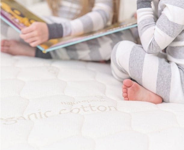 Two kids sitting on bed reading book