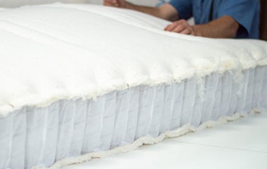 Worker attaching fluffy cotton batting to encased coil unit