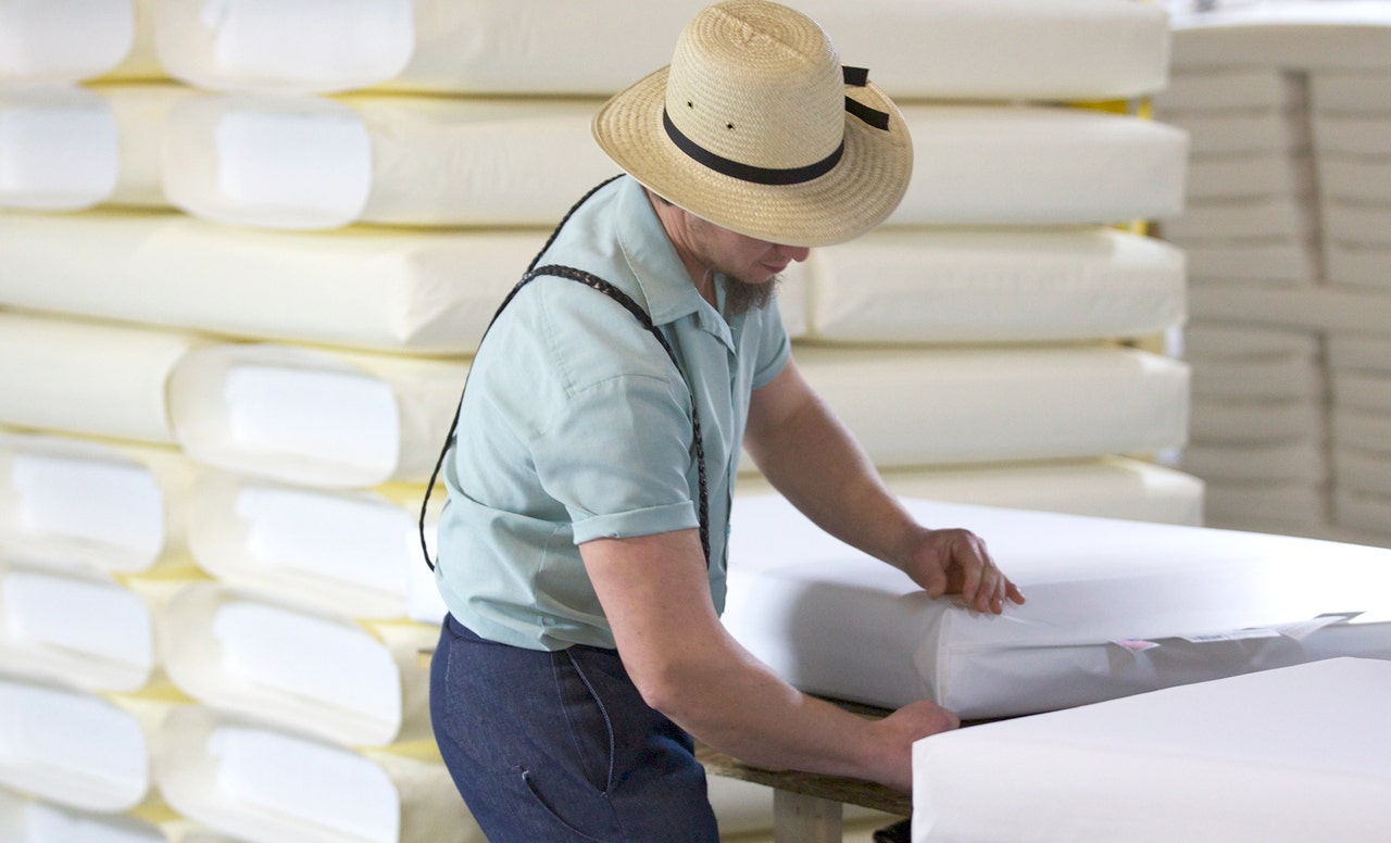 Amish worker inspecting mattress corner