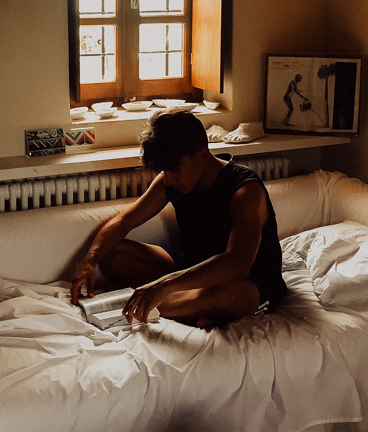 College student reading in bed instead of on screens