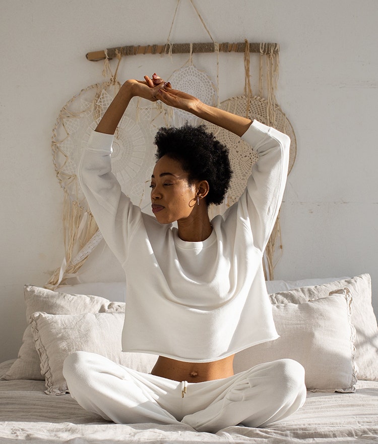 Woman stretching in bed after waking up refreshed