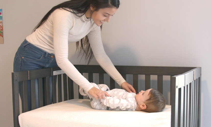 Mom smiling at baby in crib