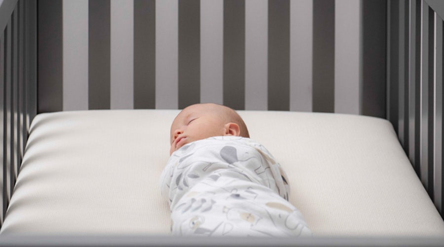 Swaddled baby sleeping on breathable organic crib mattress 