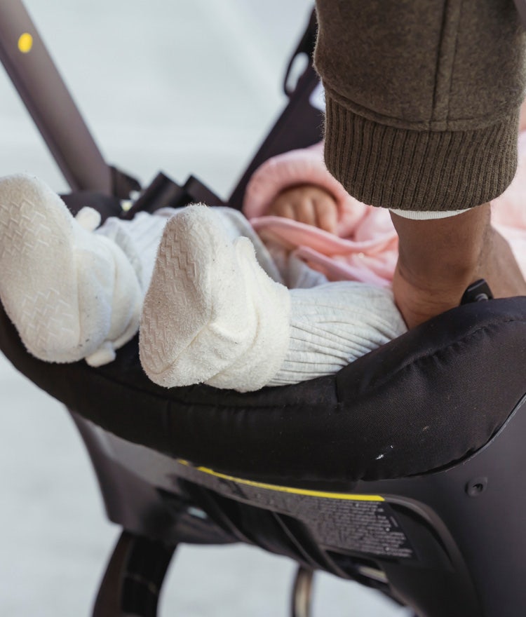 Parent placing baby in a carseat that likely contains chemical flame retardants