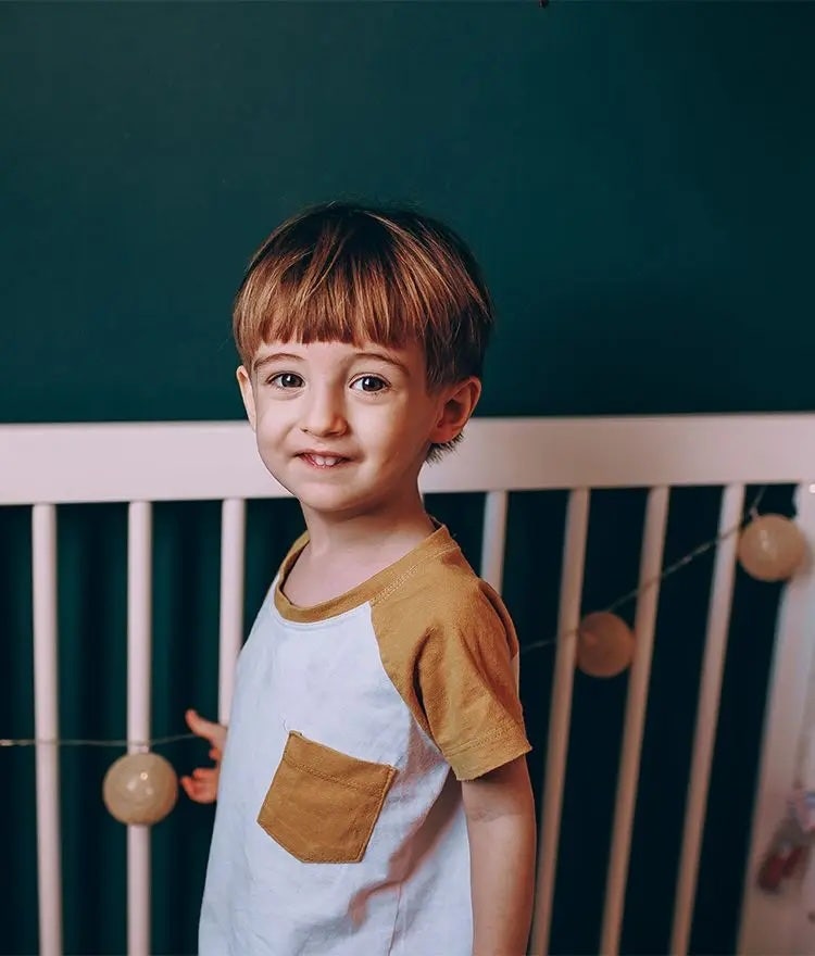 Toddler standing on crib mattress in crib