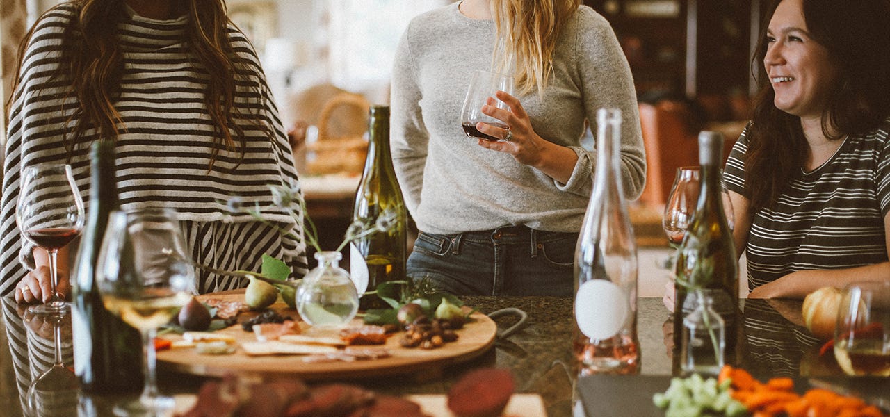 Friends at a gathering, drinking alcohol and eating standing up