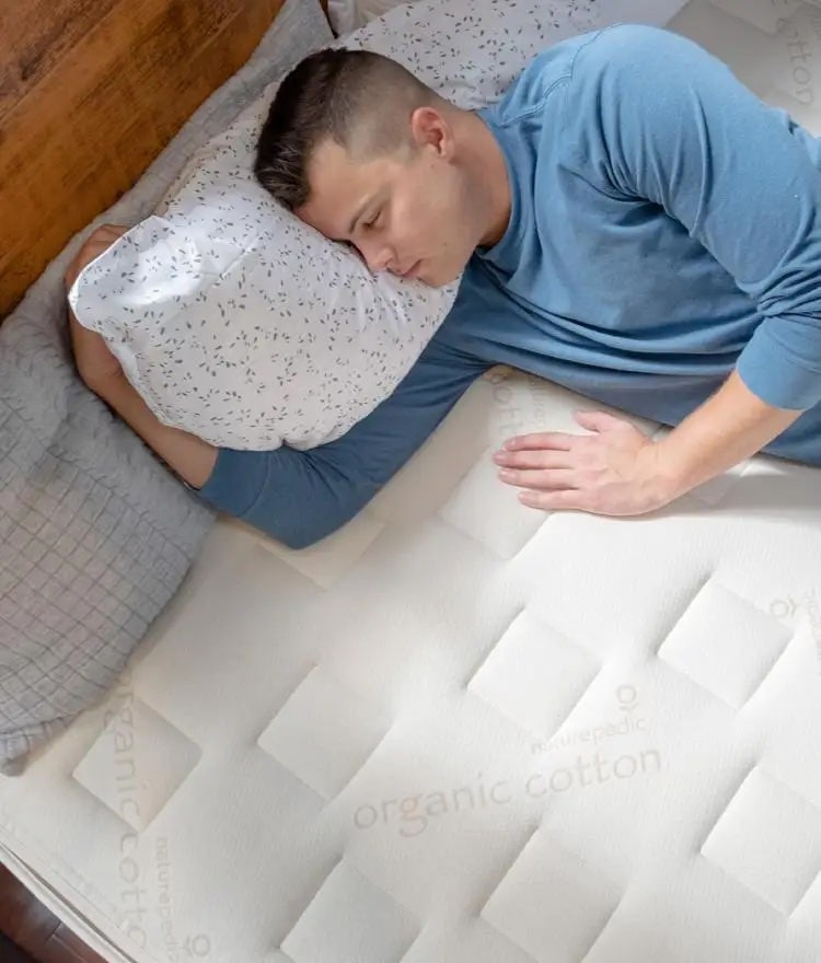 man sleeping on naturepedic organic crib mattress