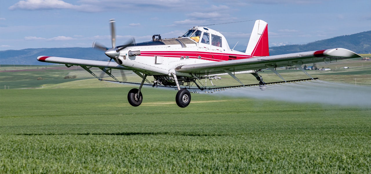 Agricultural aircraft spraying pesticides over a field