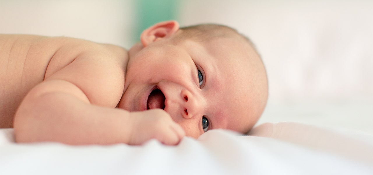 Infant lying on their tummy and smiling