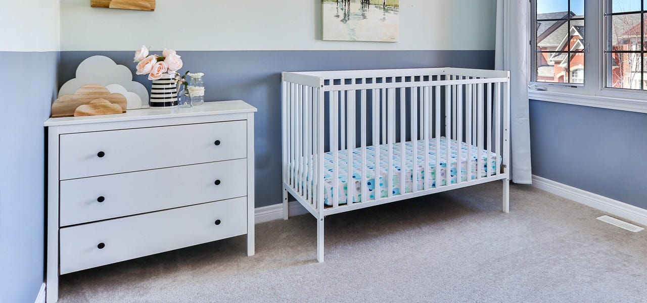 Cheerful blue nursury with a white crib and dresser