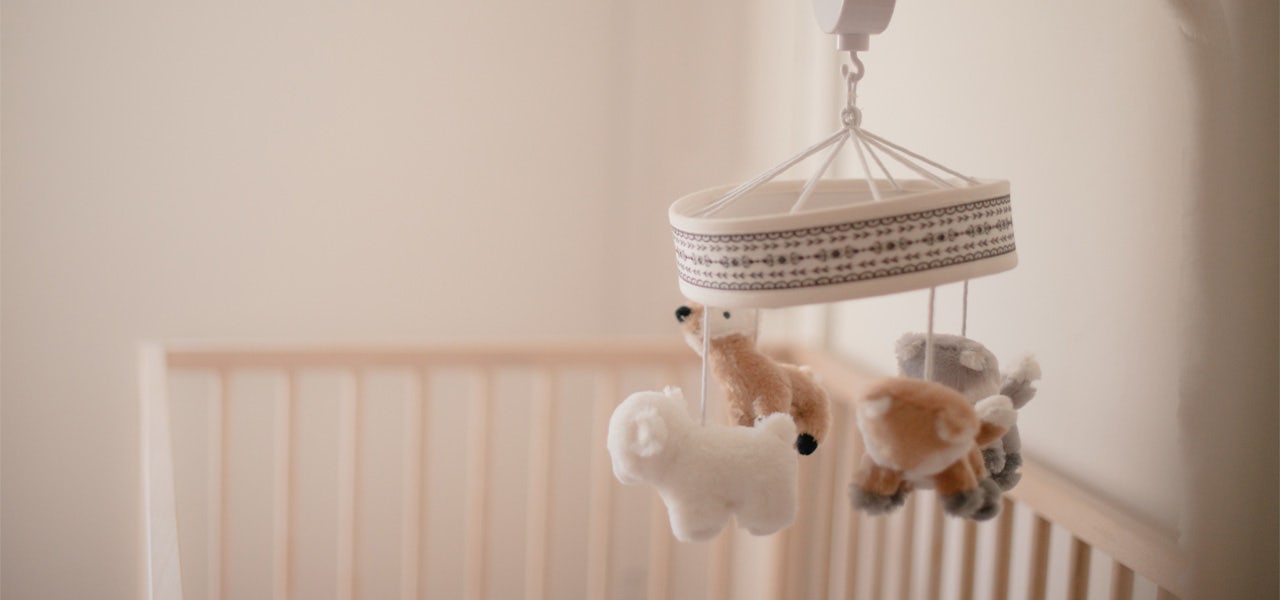 Plush animal mobile hanging over crib 