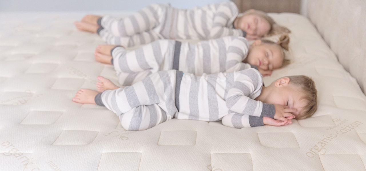 Three children of different ages sleeping on a Naturepdic organic mattress