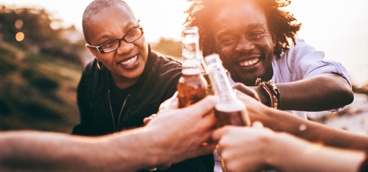 Group of friends clinking beer bottles together and smiling