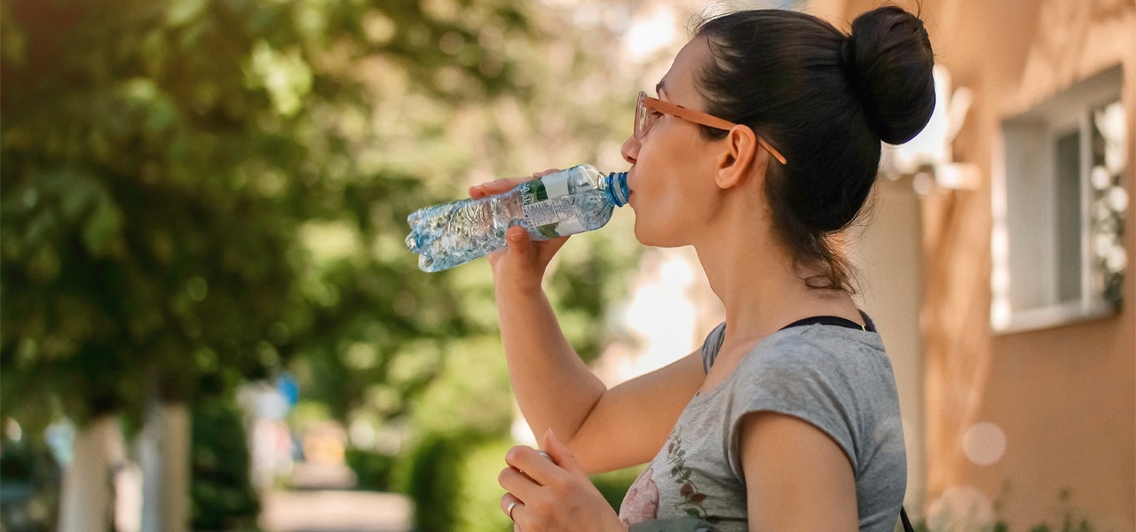 Woman outdoors and drinking water from a water bottle