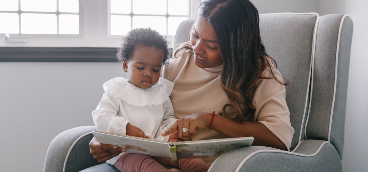 Mother reading a picture book to a small child on her lap